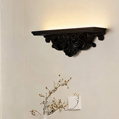 Long, flat black resin wall sconce with decorative carvings, providing upward ambient light.