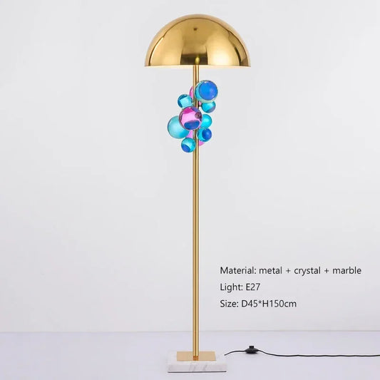 Gold dome floor lamp with a cluster of blue and pink crystal accents, on a white background.