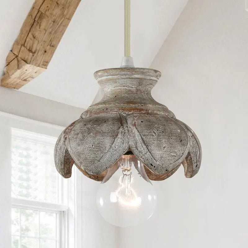 Single wood carved floral pendant light fixture with a distressed finish hanging from a beam.