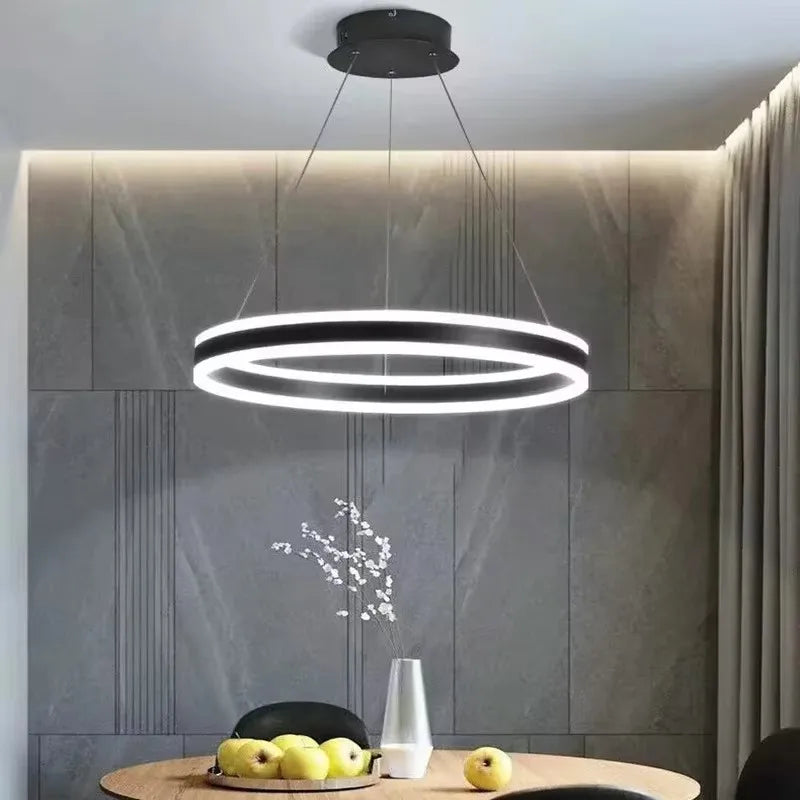 A circular pendant light with a black and white frame, casting light in a modern dining area.