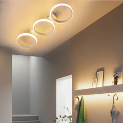 White LED ceiling light with three interconnected rings mounted on a hallway ceiling.