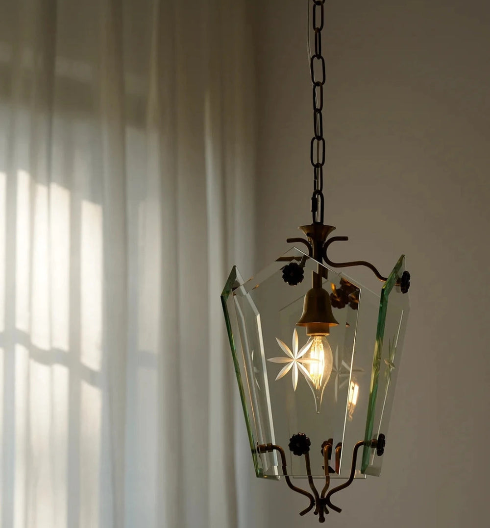 Vintage-style pendant light with glass shade and brass fixture against a neutral wall.
