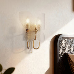 Gold butterfly wall sconce installed next to a bed, showing its decorative appeal in a bedroom setting.
