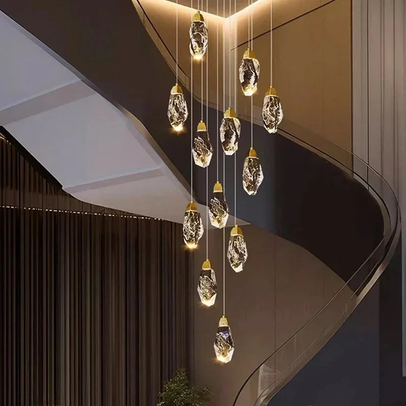 Close-up view of a cascading gold chandelier, showing the intricate detail of the faceted crystal drops and their warm LED illumination against a blurred modern interior.