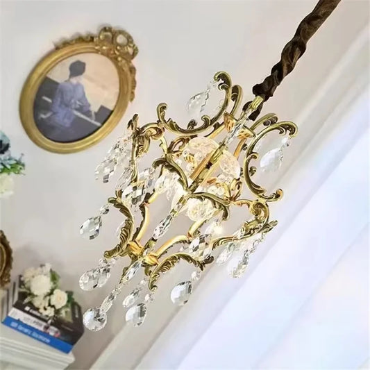 Close-up of a gold ornate chandelier with clear teardrop crystals cascading down.