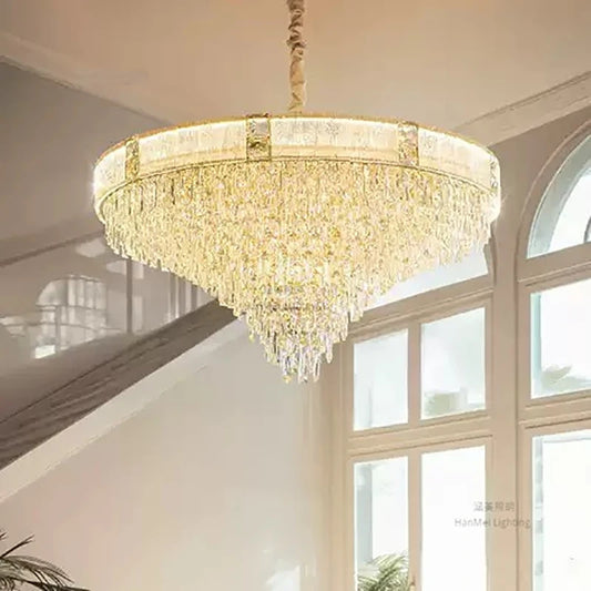 A wide shot of a grand staircase with a large gold chandelier featuring cascading crystals hanging above.