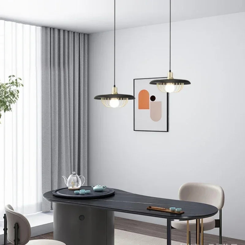 Wood-finish pendant light with gold cage hanging in a modern dining room setting.