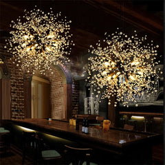 Two dandelion starburst pendant lights with warm illumination hanging over a wooden bar counter in a dimly lit room.