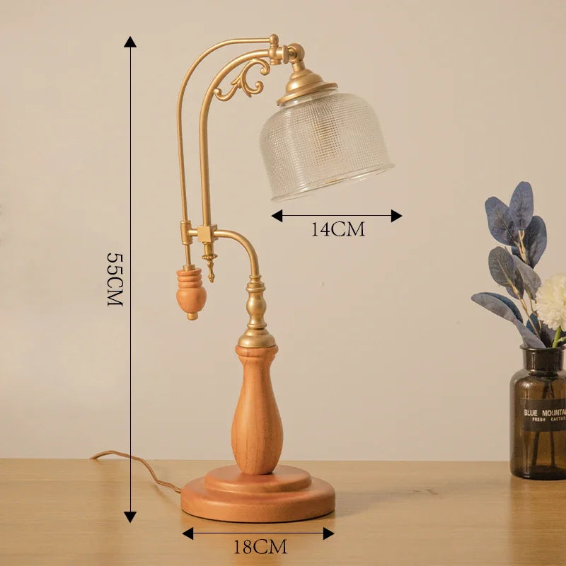 Table lamp with wooden base and gold metal arm, dimensions indicated, on a beige background.
