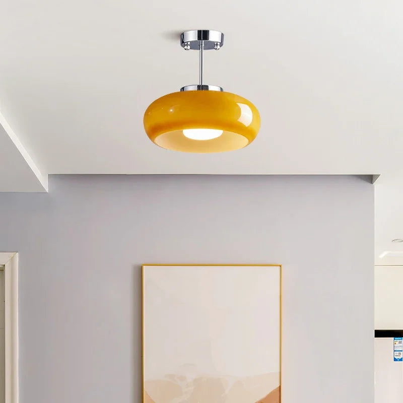 Single yellow glass dome semi-flush mount light with a brass finish on a grey ceiling
