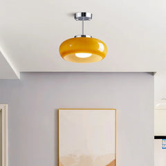 Single yellow glass dome semi-flush mount light with a brass finish on a grey ceiling
