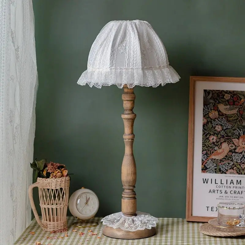 Close-up of the fabric and lace detail on the lampshade of a wooden table lamp.
