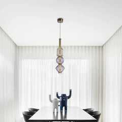 Modern pendant light with a clear glass orb shade and brushed gold hardware hanging over a dining table.