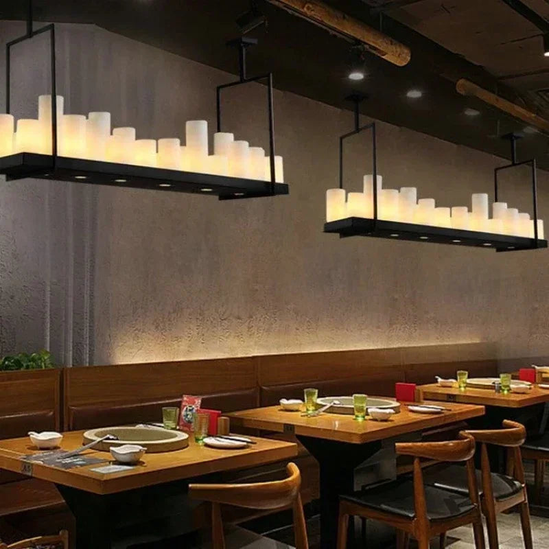 Dining area with wooden tables, chairs, and hanging light fixtures in a restaurant setting.