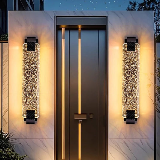 Close-up of a gold wall sconce featuring a tall, rectangular bubble crystal shade and metallic accents.