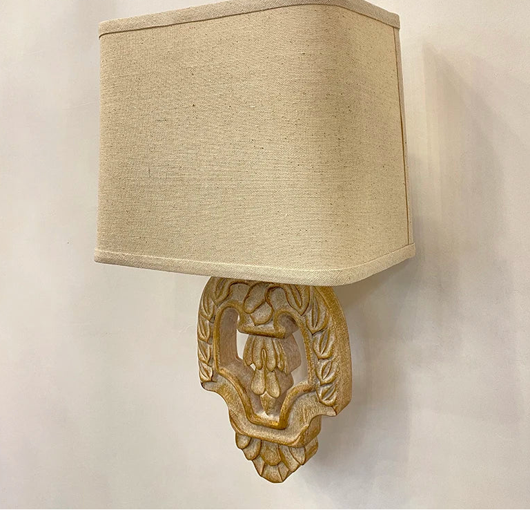 Beige wall lamp with decorative base on a plain background.