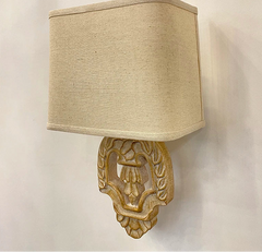 Beige wall lamp with decorative base on a plain background.