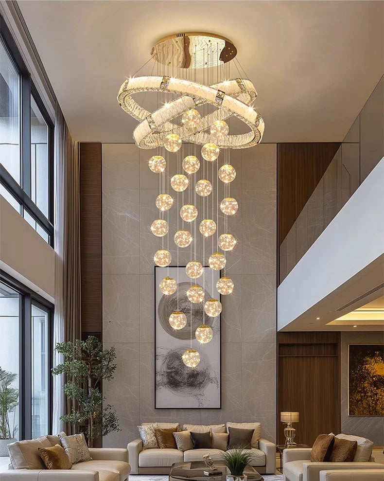 Luxury chandelier hanging in a modern living room with large windows and a sofa.