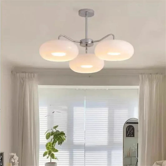 Three white globe shades on a chrome multi-arm chandelier in a bright room