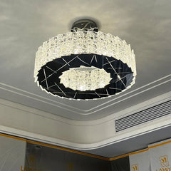 Angled view of a modern spiral crystal flush mount chandelier with a dark metallic interior, installed on a white ceiling with decorative molding.
