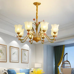 Wide view of a gold floral ceramic chandelier with multiple arms and glass shades in a living room setting.