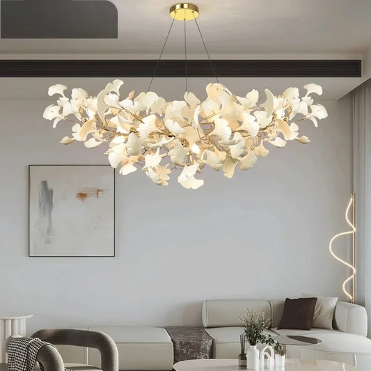 Gold ginkgo leaf cluster pendant light hanging above a sofa in a modern living room