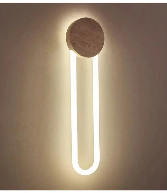 Close-up of a modern wall sconce with a textured stone circle above a U-shaped yellow LED light.