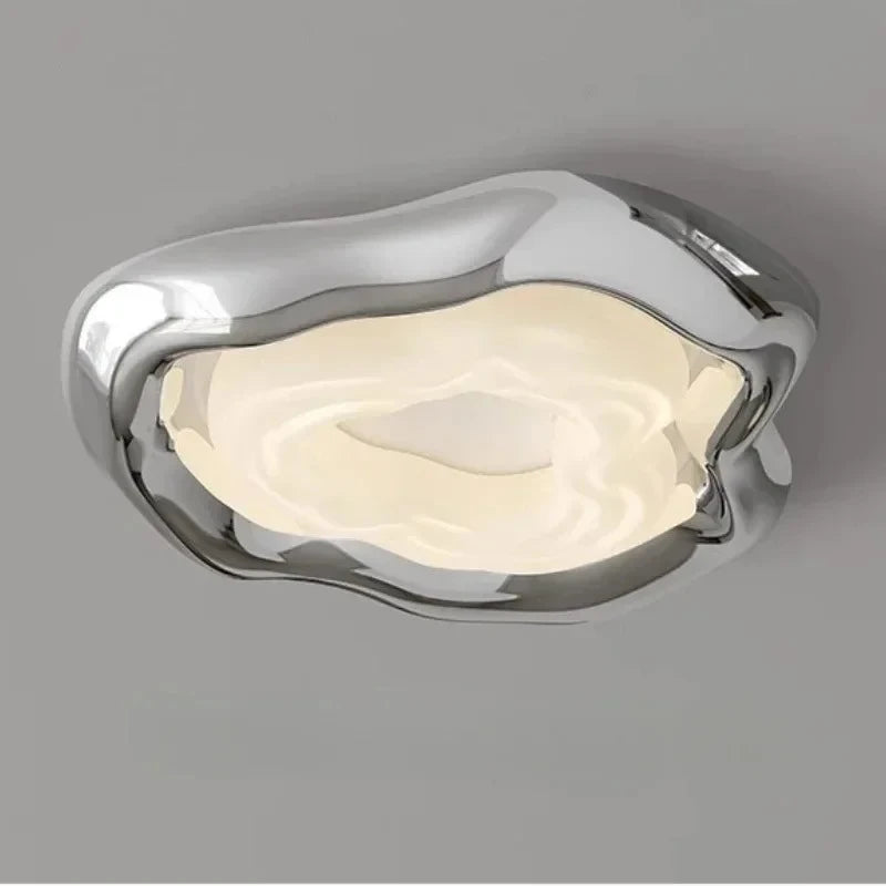 Close-up of a modern chrome ceiling light with an organic, wavy design and a diffused light source.