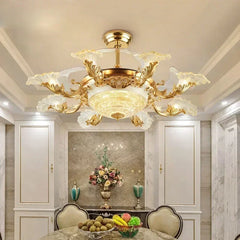 An angled view of a gold ceiling fan light featuring a central glass diffuser and intricate floral crystal arms, illuminating a dining area.