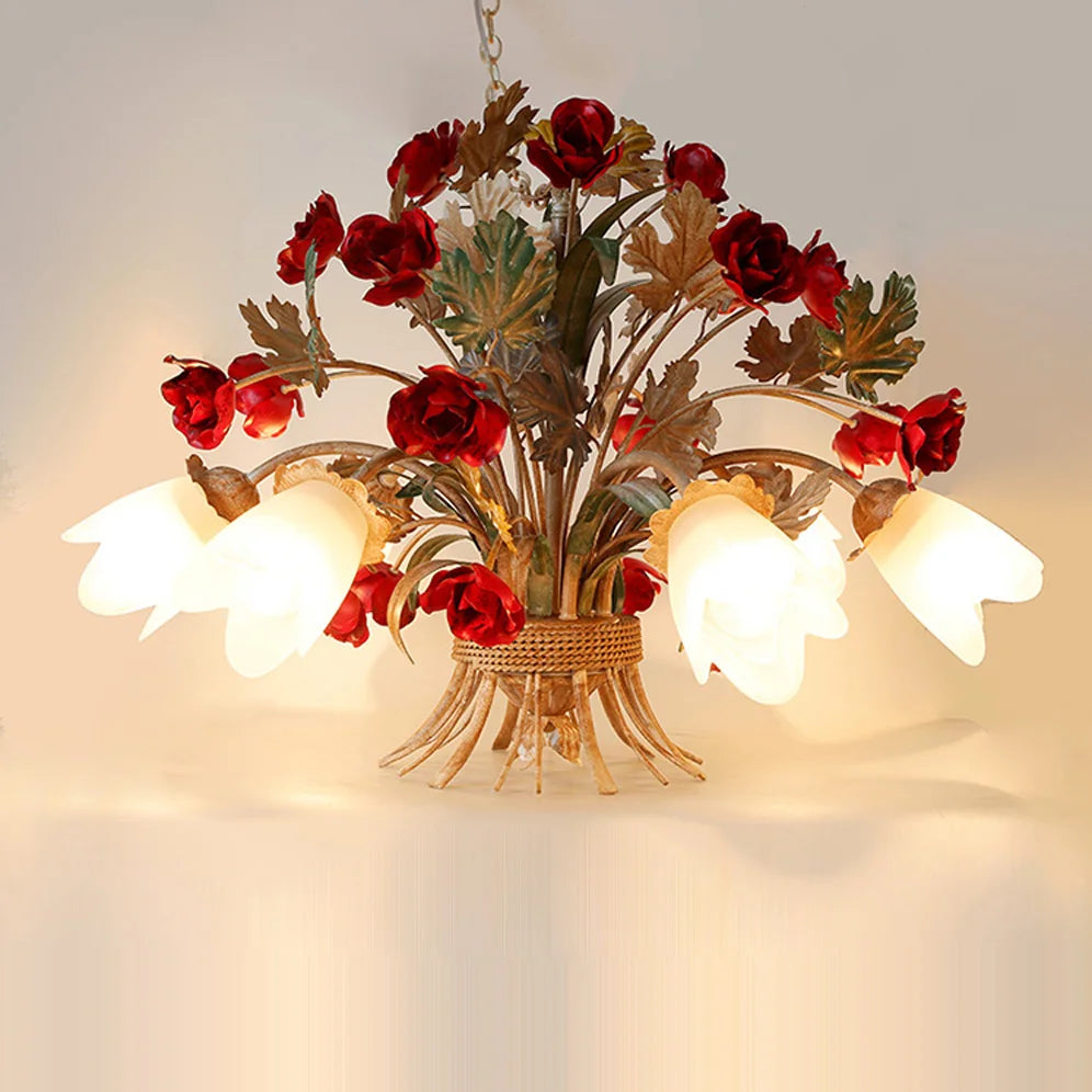 A gold floral pendant light with red rose buds and frosted glass shades mounted on a white wall, showcasing its intricate design.