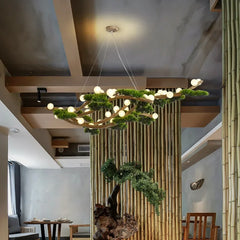 A botanical chandelier with a wood branch structure and LED lights, viewed from a slightly lower angle in a room with bamboo wall paneling.