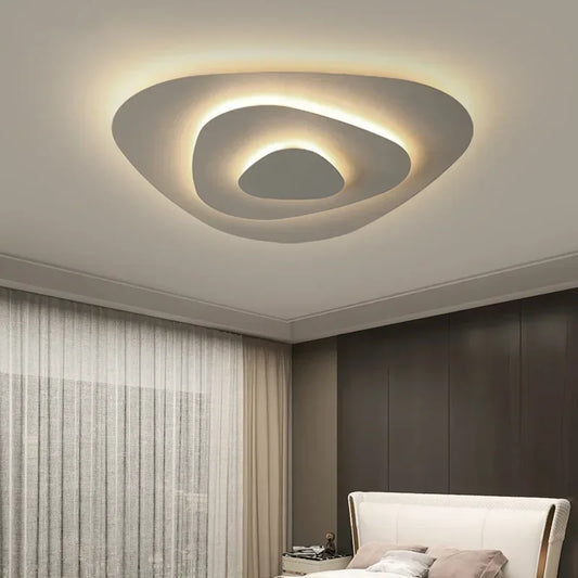 A modern, multi-layered flush mount ceiling light with an irregular, organic shape in white, emitting a warm, diffused glow.