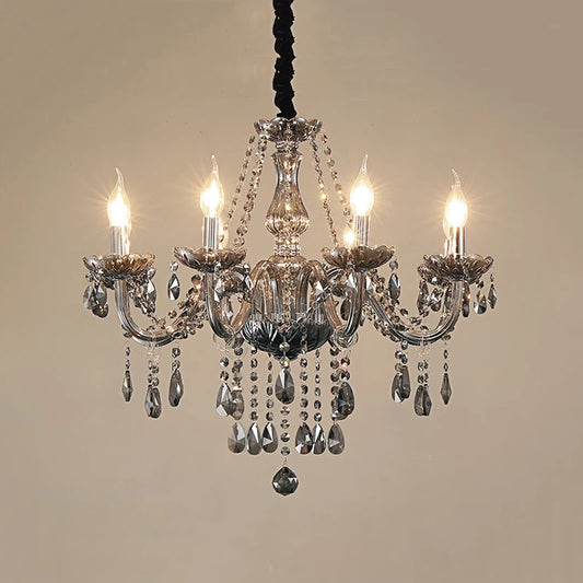 A smoke gray crystal chandelier with lit candle-style bulbs and numerous crystal accents, suspended against a plain background.