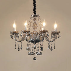 A smoke gray crystal chandelier with lit candle-style bulbs and numerous crystal accents, suspended against a plain background.