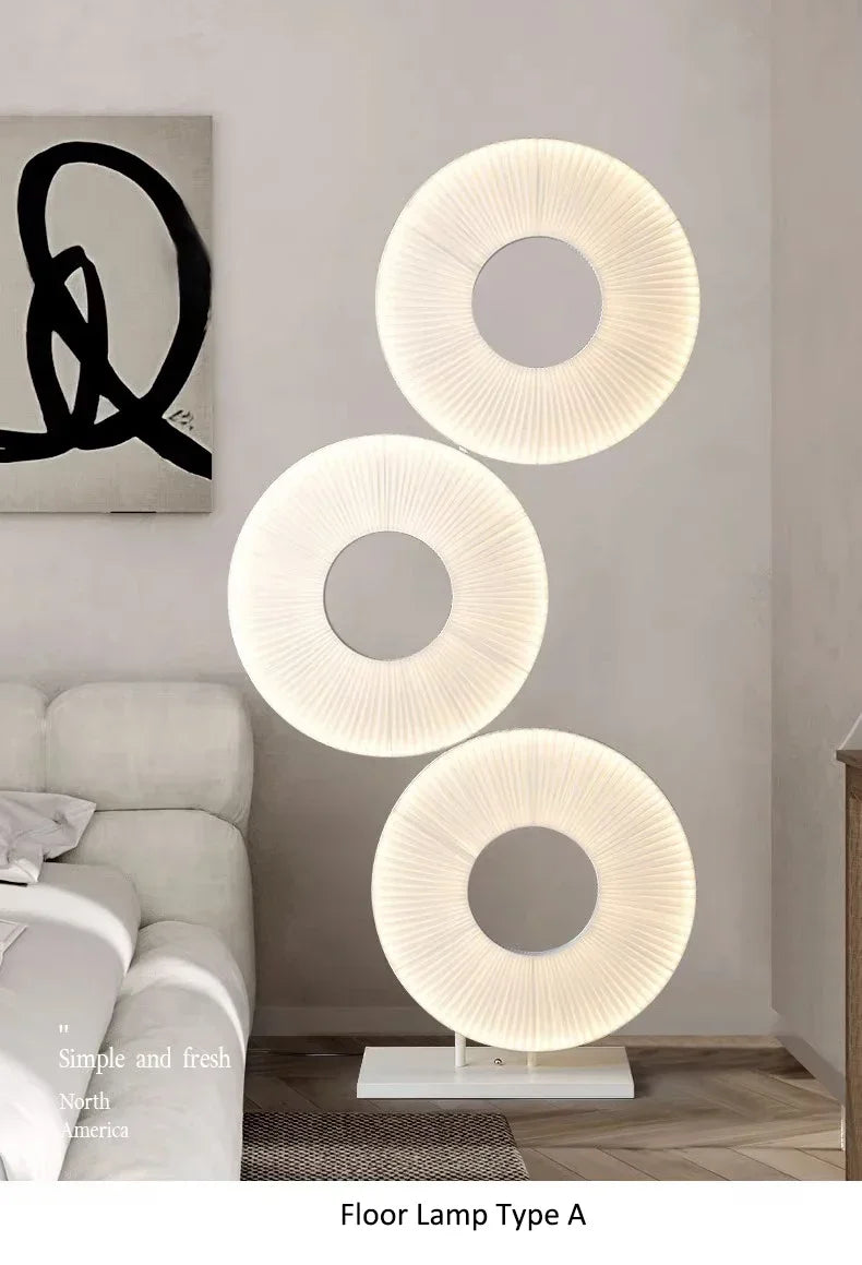 Modern floor lamp with three circular shades in a living room setting.
