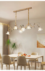 Gold floral pendant light installed over a dining table, casting a warm glow.