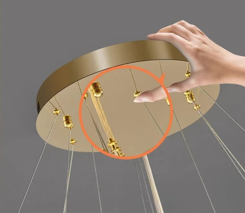 Gold circular light fixture with hand adjusting it against a gray background