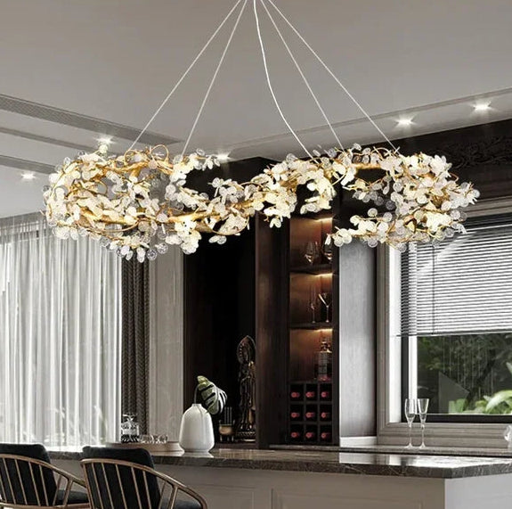 Modern chandelier hanging in a stylish interior setting with a kitchen in the background.
