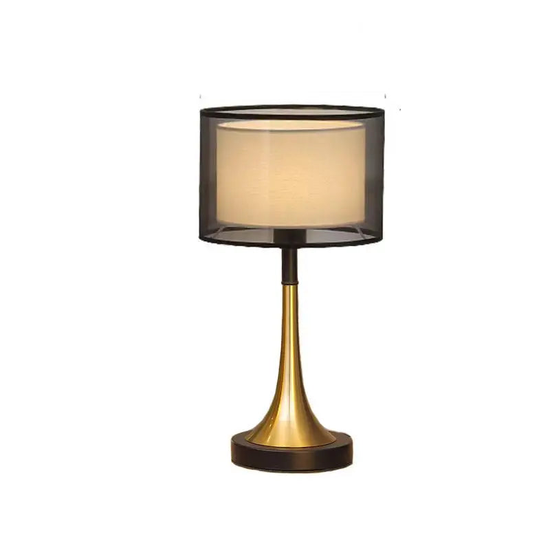 Table lamp with black shade and gold base on a white background