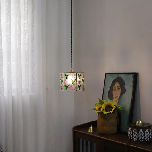Glass floral pendant light hanging in a room with sheer curtains and artwork