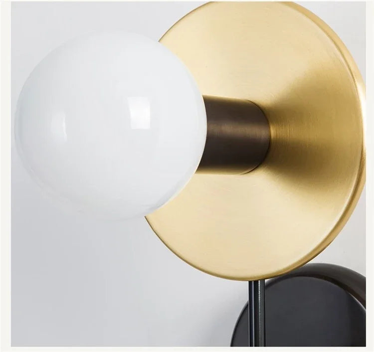 Gold wall sconce with a white bulb on a light gray background