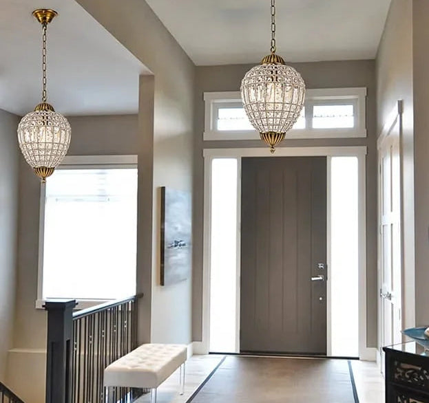 Foyer with crystal chandeliers, a door, and a bench.