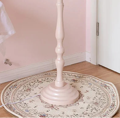 Round patterned rug on a wooden floor with a white table and plant in the background.