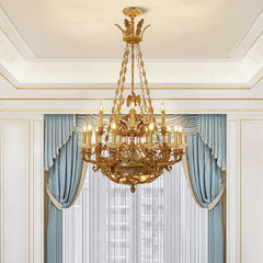 Gold candelabra crystal chandelier with blue curtains in the background.