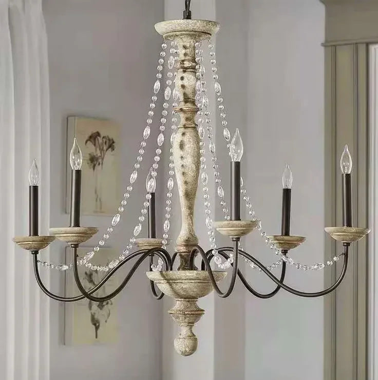 A close-up view of a distressed wood candelabra chandelier adorned with clear crystal beads and candle-style light bulbs.