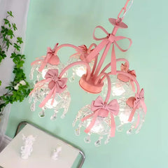 Angled view of a pink multi-arm chandelier with decorative pink bows and crystal teardrops, showing its intricate design.