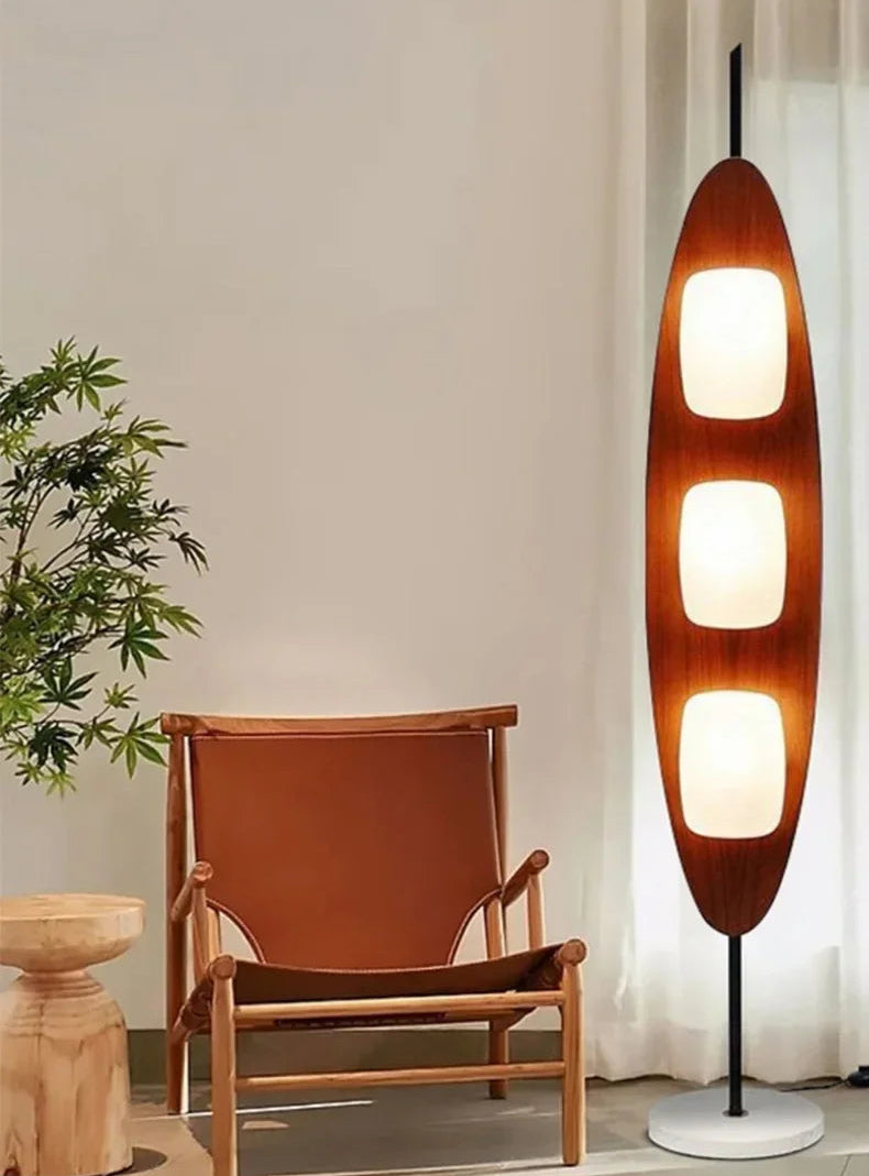 Wooden floor lamp next to a chair and plant in a room setting