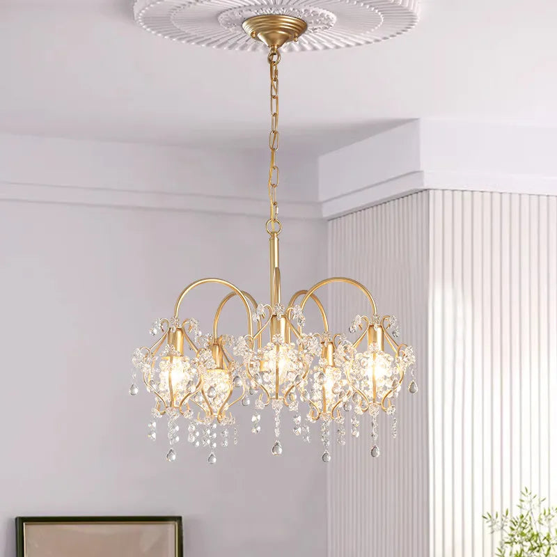 An overhead view of the gold crystal chandelier, showing its placement against a decorative ceiling medallion and the chain suspension.