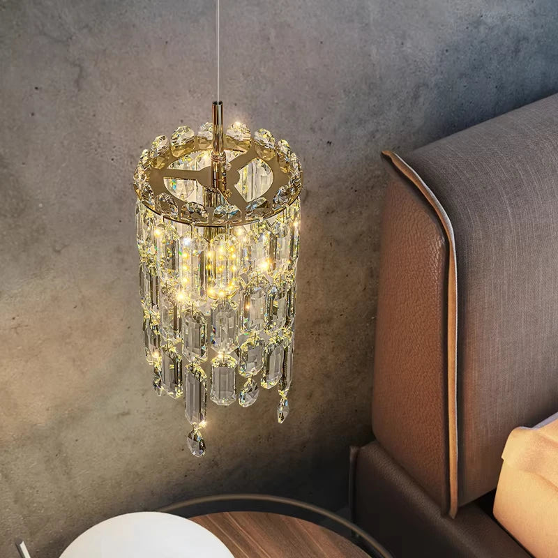 Gold tiered crystal pendant light hanging next to a bed