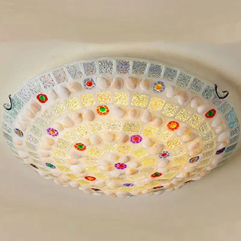 Detailed view of the colorful glass and shell mosaic pattern on a flush mount ceiling light.